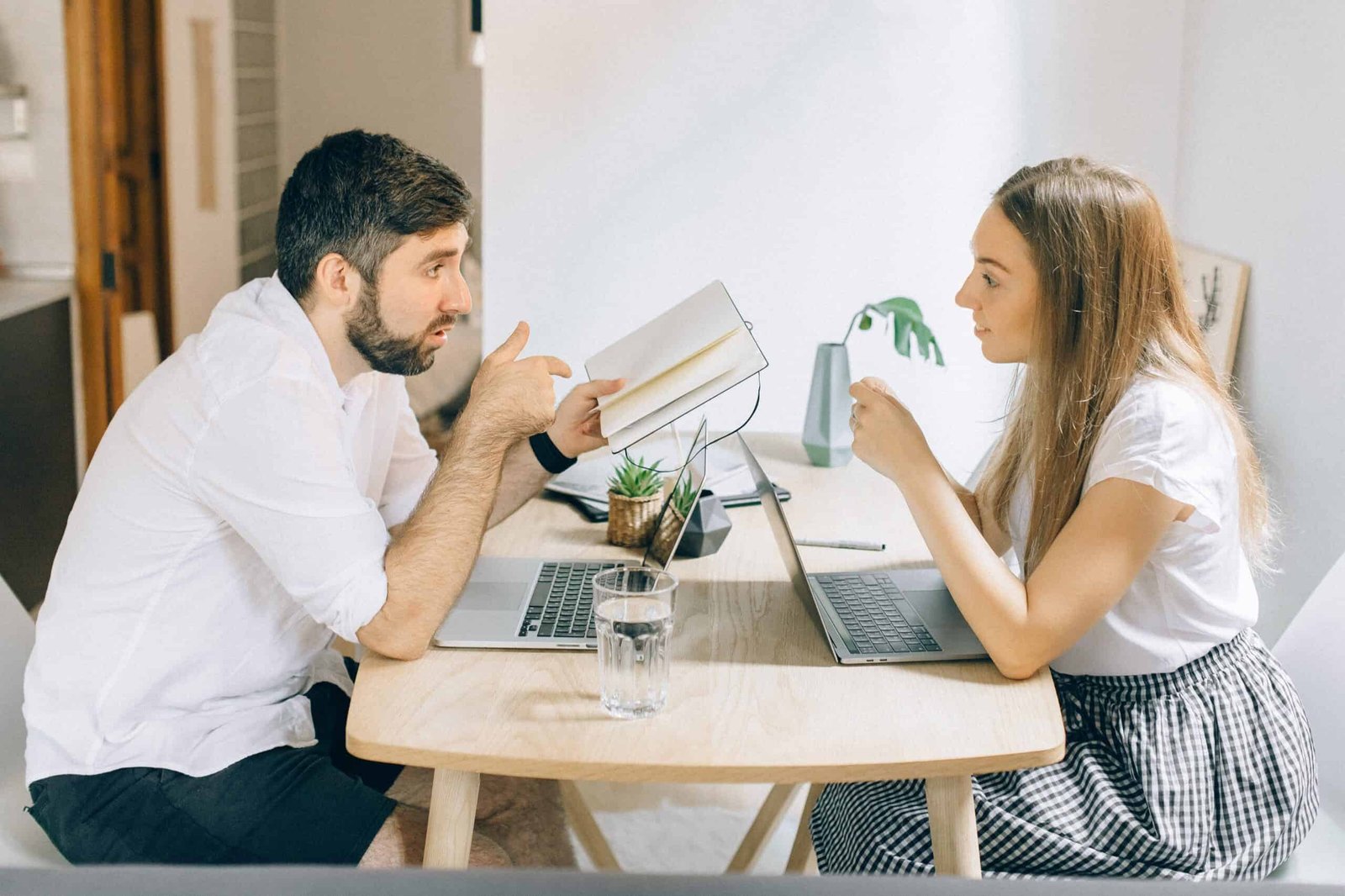 A young couple effectively communicates in their home office, with the wife listening intently while the husband reviews their weekly budget.