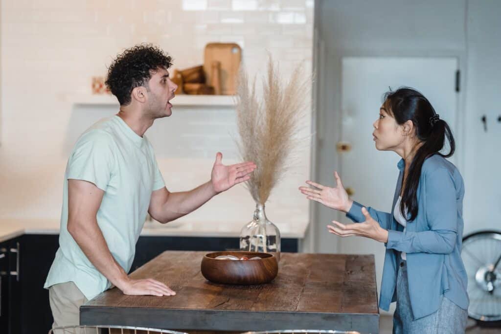 A couple is having heated arguments around their dining table and pointing at each other