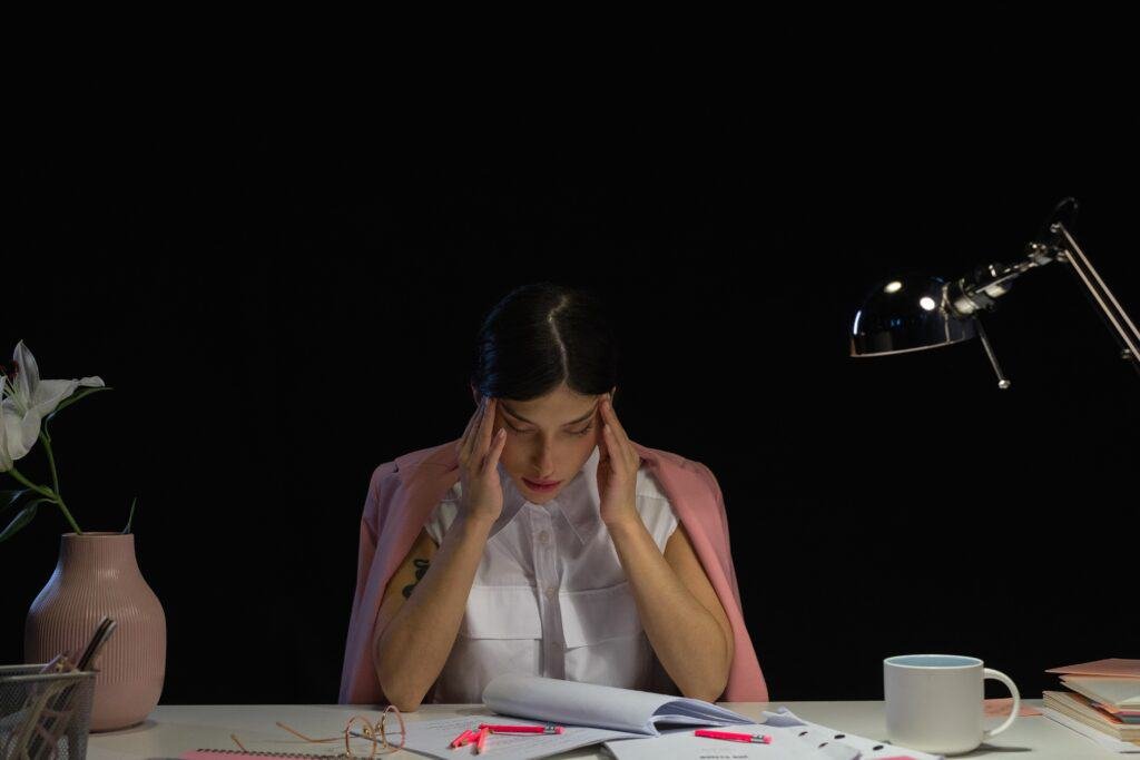A female workaholic executive feeling overwhelmed due to her massive work load.