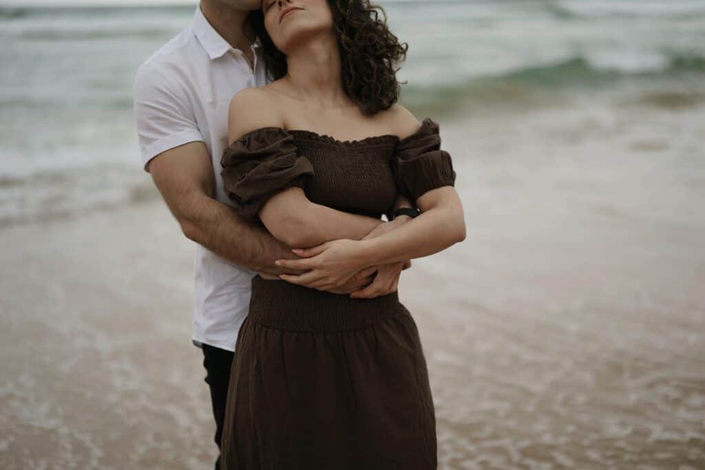 A Black couple cuddling on the beach as a display of meeting each other's emotional needs