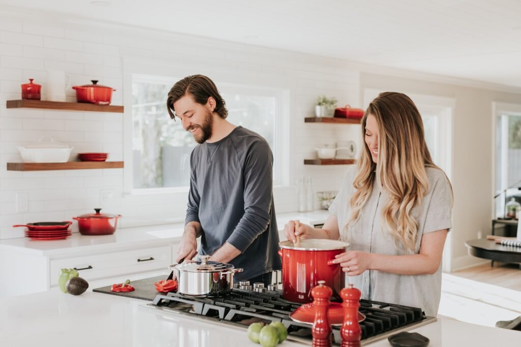 A young couple who are cooking together in their kitchen smiling about their friendship in marriage