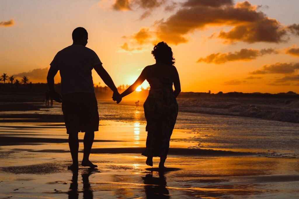 A silhouette of a couple walking by the beach at sunset as they meet each other's physical needs in marriage.