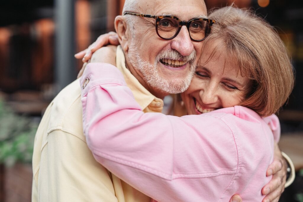 An older couple who are smiling happily while cuddling together as a display of their friendship in marriage