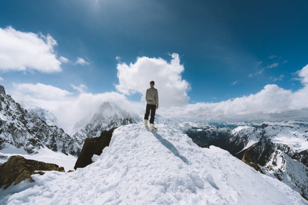 A man standing on a snowy mountain peak viewing clear blue sky as opportunity knocks for a beautiful adventure