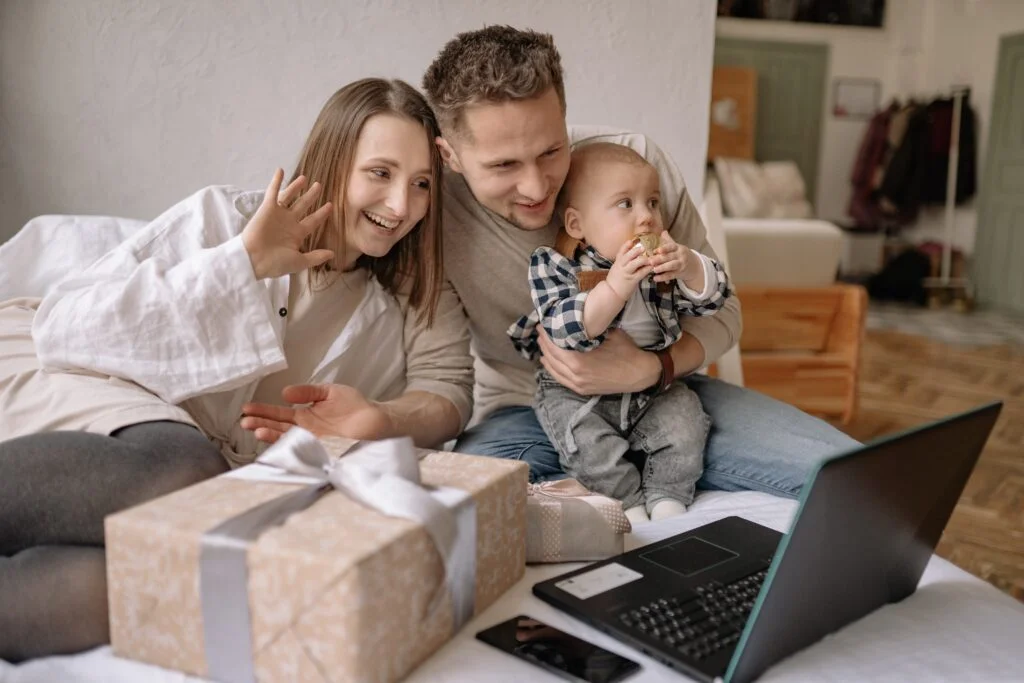 A couple holding their new born baby while conducting a Zoom video call with their family during the holidays.