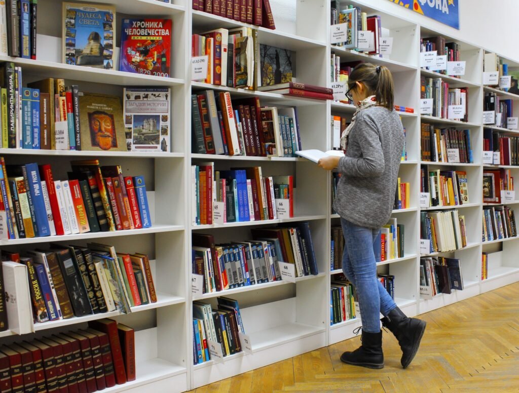A female student searching for personal growth and development books in the library racks.
