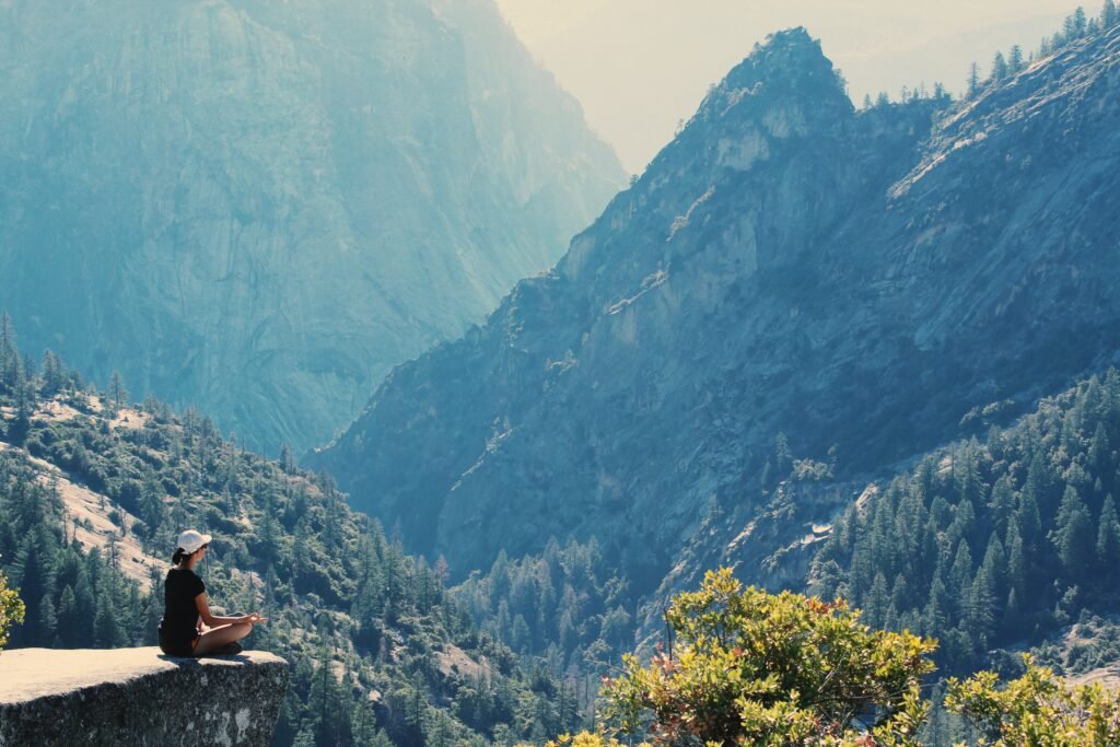 A lady seated on a ledge meditating while taking in the awesome views of the mountain.