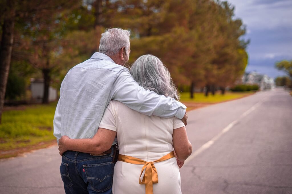 Elderly couple holding hands and walking down a road in long-term relationships