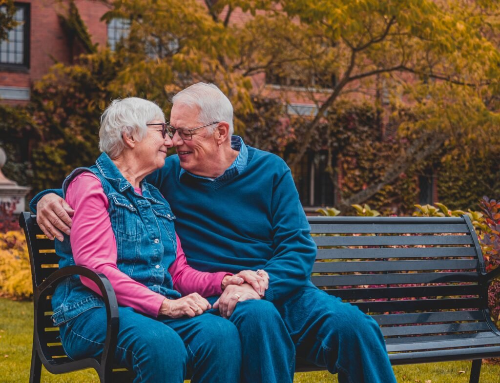 Elderly Black couple seated at a bench while smiling to each other in long-term relationships