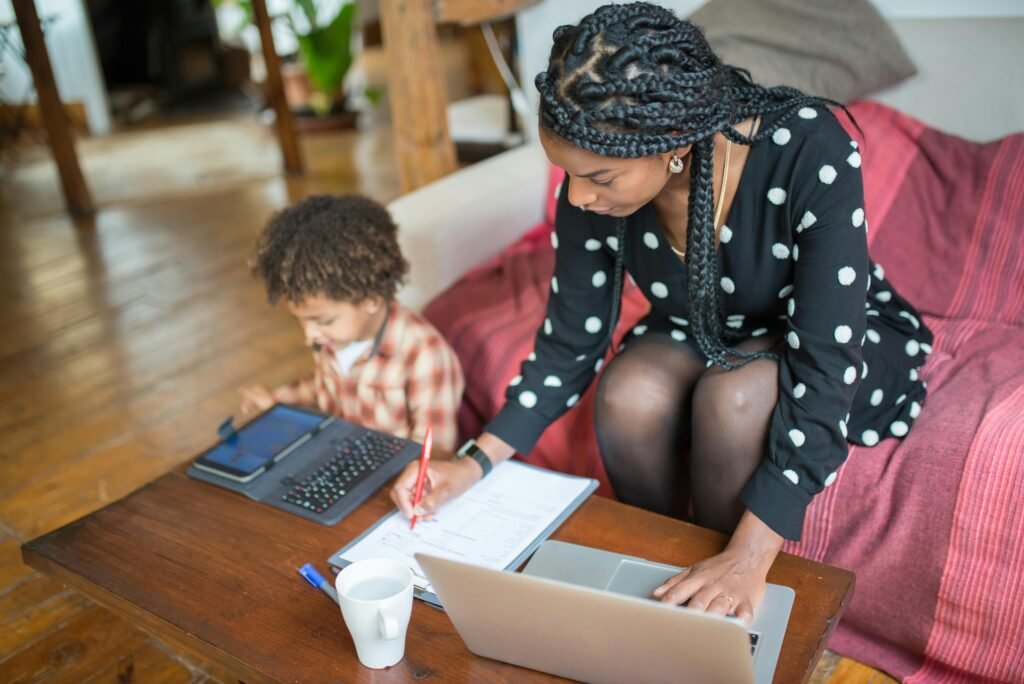 A photo showing a mum working from home while guiding her son in honoring motherhood.