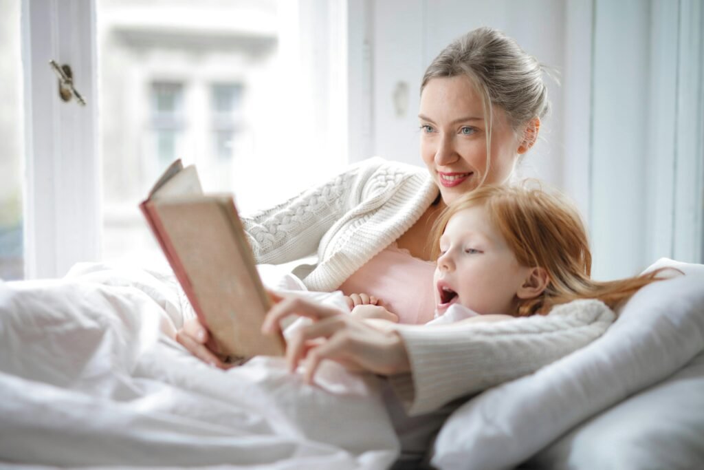 A mum lays cosily on the sofa while reading to her daughter on Mother's Day.
